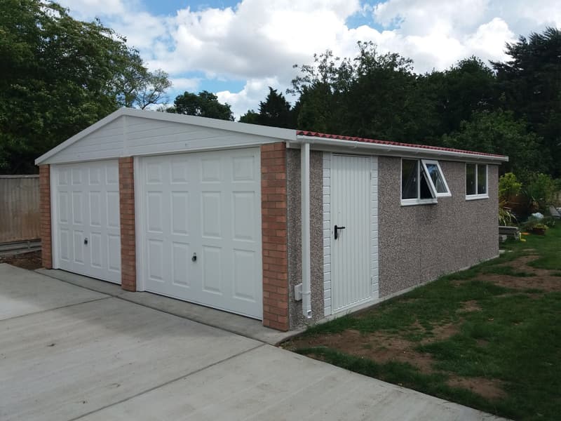 Nucrete double apex concrete garage with white doors installed on a new concrete driveway