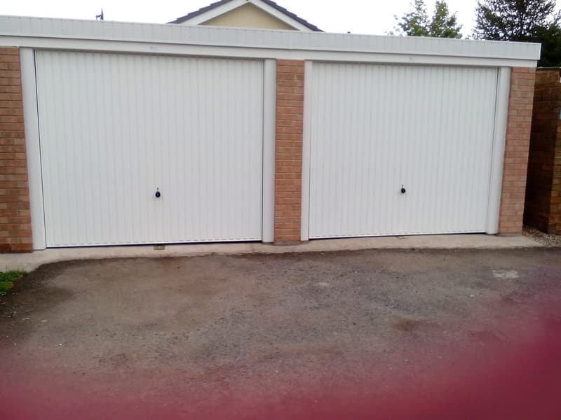 Double pent-roof concrete garage with two white up-and-over doors